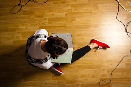 young woman sitting on the floor and reading a bookの写真素材