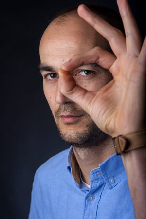 casual male portrait looking through circle made with handの写真素材