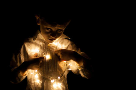 little boy portrait whit christmas lights in his handの写真素材