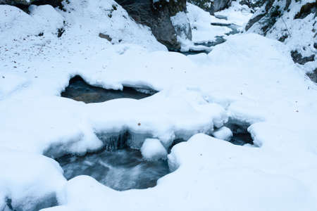 white snow covered cold creek in winter timeの写真素材