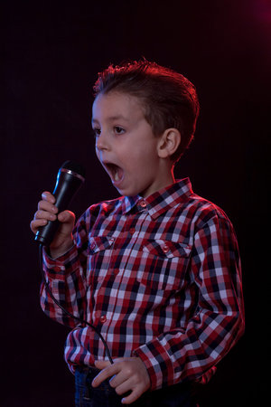 young boy in red and blue back light yelling in microphoneの写真素材