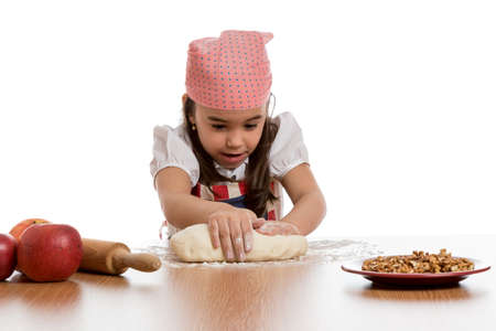 young little girl preparing dough at table with apples and rolling pinの写真素材
