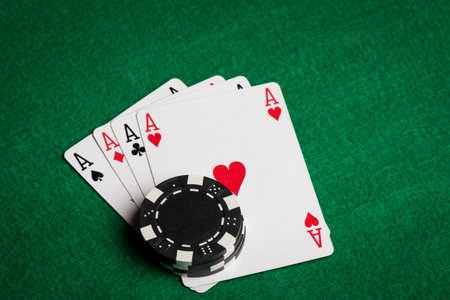 four aces and black chips on a green table