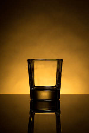 one back lit empty whiskey glass with reflectionの写真素材