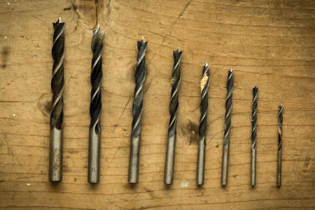set of used drill bits on wooden tableの写真素材
