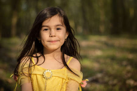 little girl in yellow princess dress in forestの写真素材