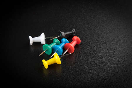 different color office pins on a black tableの写真素材