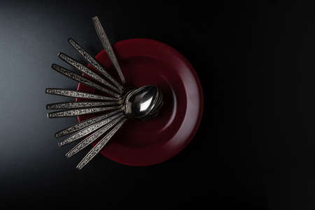 abundance of spoons in marsala color plate on black tableの写真素材
