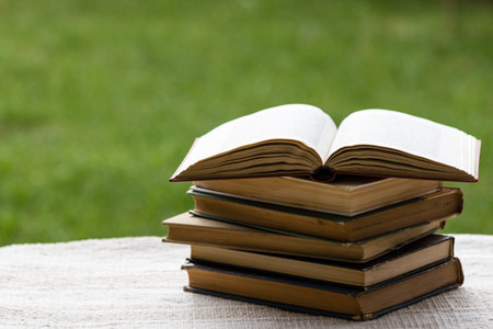 stack of books on table in garden with top one opened