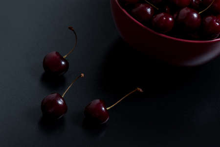 fresh natural cherries in a bowl on black tableの写真素材