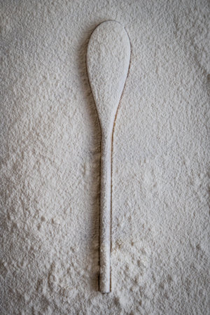 wooden spoon covered in white flour on tableの写真素材