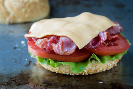 breakfast sandwich with egg, bacon, cheese and vegetables on steel plateの写真素材