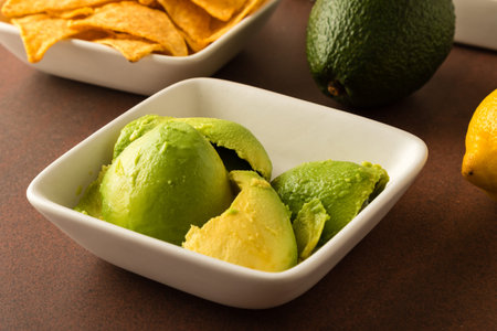 preparing of guacamole with avocado, lemon, onion, and tortilla chipsの写真素材