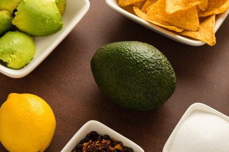 preparing of guacamole with avocado, lemon, onion, and tortilla chipsの写真素材