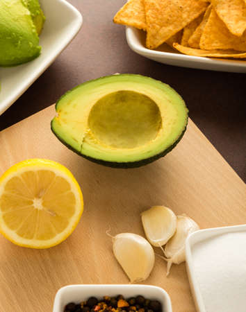 preparing of guacamole with avocado, lemon, onion, and tortilla chipsの写真素材