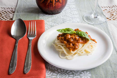 spaghetti bolognese on a white plate with basil leafの写真素材