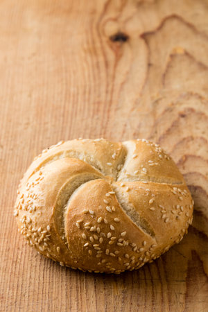 Round sandwich bun with sesame seeds on wooden tableの写真素材