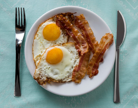 bacon and eggs breakfast on a white plateの写真素材