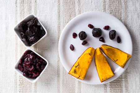 baked pumpkin on white plate with prunes and cranberryの写真素材