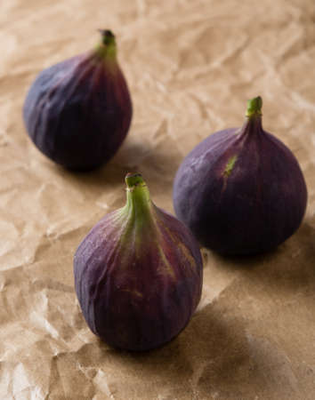 three natural ripe figs on brown paperの写真素材