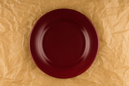 empty red shiny plate on brown paper background