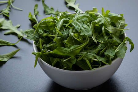 rucola salad in white bowl on black tableの写真素材