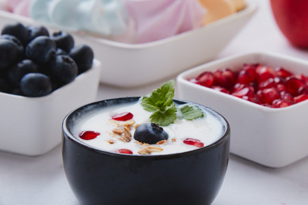 yogurt with cereals, blueberry and pomegranate in a black bowlの写真素材