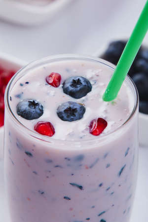 blueberry smoothie in glass with green strawの写真素材