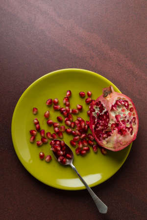 cut pomegranate and seeds on a green plateの写真素材