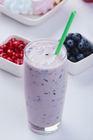 blueberry smoothie in glass with green strawの写真素材