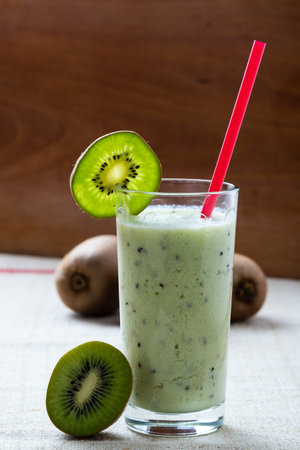 fresh green kiwi smoothie in glass with red strawの写真素材