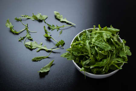 rucola salad in white bowl on black tableの写真素材