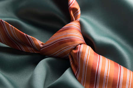 elegant casual orange necktie knot on green silkの写真素材