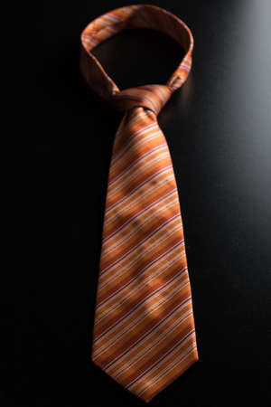 elegant casual orange neck tie on black tableの写真素材