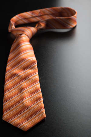elegant casual orange neck tie on black tableの写真素材