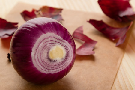 peeled fresh purple onion and onionskin on table