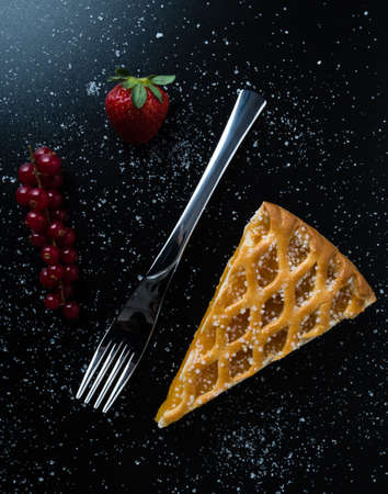 fresh apple pie slice on black table with currant and strawberryの写真素材