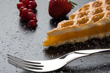 apple pie slice close-up on black table with currant and strawberry