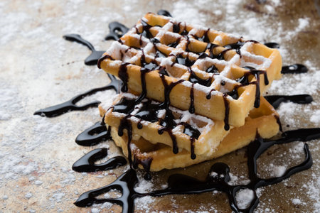 waffle with chocolate syrup on a sugary steel plateの写真素材