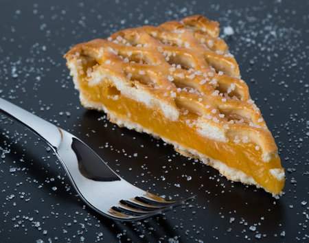 fresh apple pie slice on black table with fork and sugar