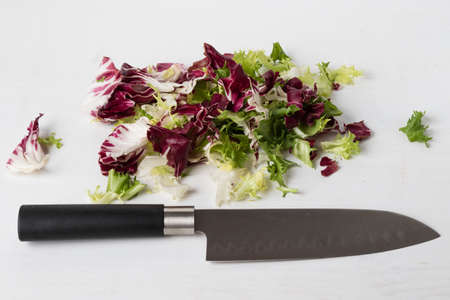 colorful chopped lettuce on white wooden table with knifeの写真素材