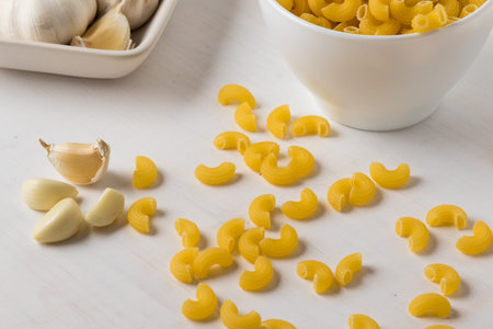 raw uncooked yellow macaroni on white wooden table