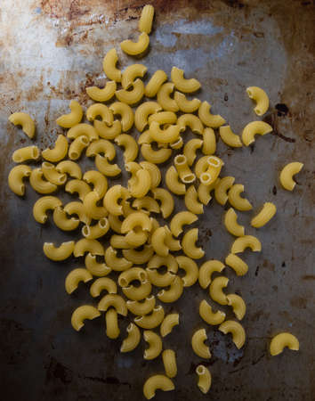 raw uncooked yellow macaroni on steel plate