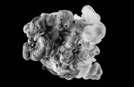 Abstract acrylic black and white paint swirls in water on black background