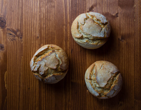round fresh bread bun on brown wooden tableの写真素材