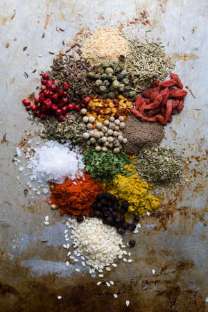 abundance of different color spices on steel plate
