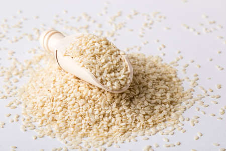 nutritious yellow sesame seeds on white table with scoopの写真素材