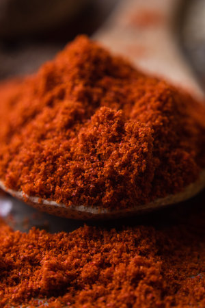 close up of red paprika spice powder on wooden spoon