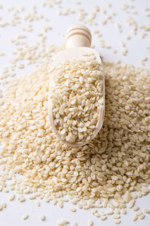 nutritious yellow sesame seeds on white table with scoopの写真素材