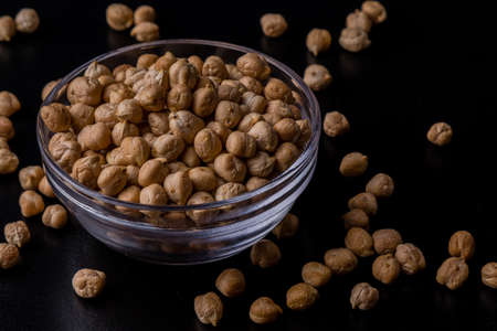 dry brown chickpeas in a bowl on black tableの写真素材